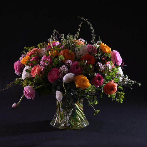 Colorful ranunculus and garden roses in glass vase by Raleigh florist