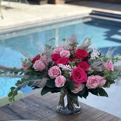 Blush and hot pink roses with pampas grass and eucalyptus in a clear vase poolside, premium Raleigh florist
